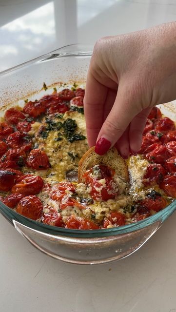 a person dipping some food into a glass bowl on top of a white countertop