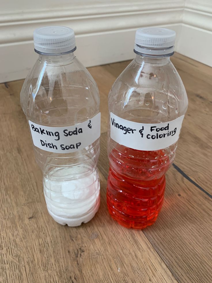 two plastic water bottles filled with liquid sitting on top of a wooden floor