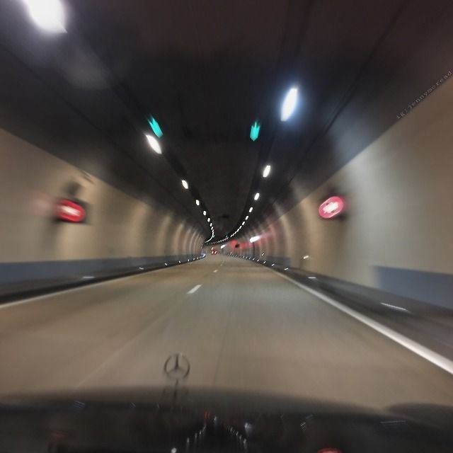 a car driving through a tunnel with lights on