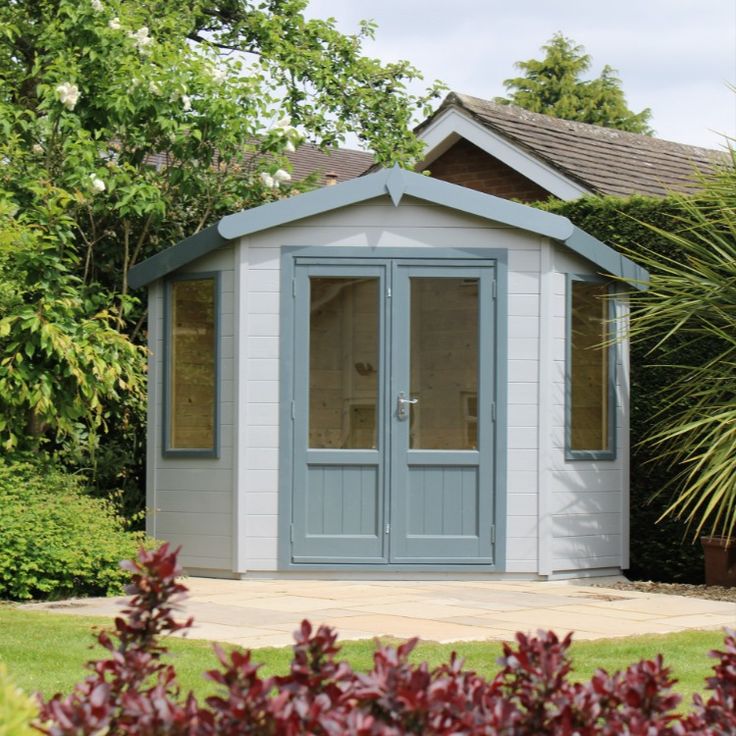 a small blue and white shed sitting in the grass