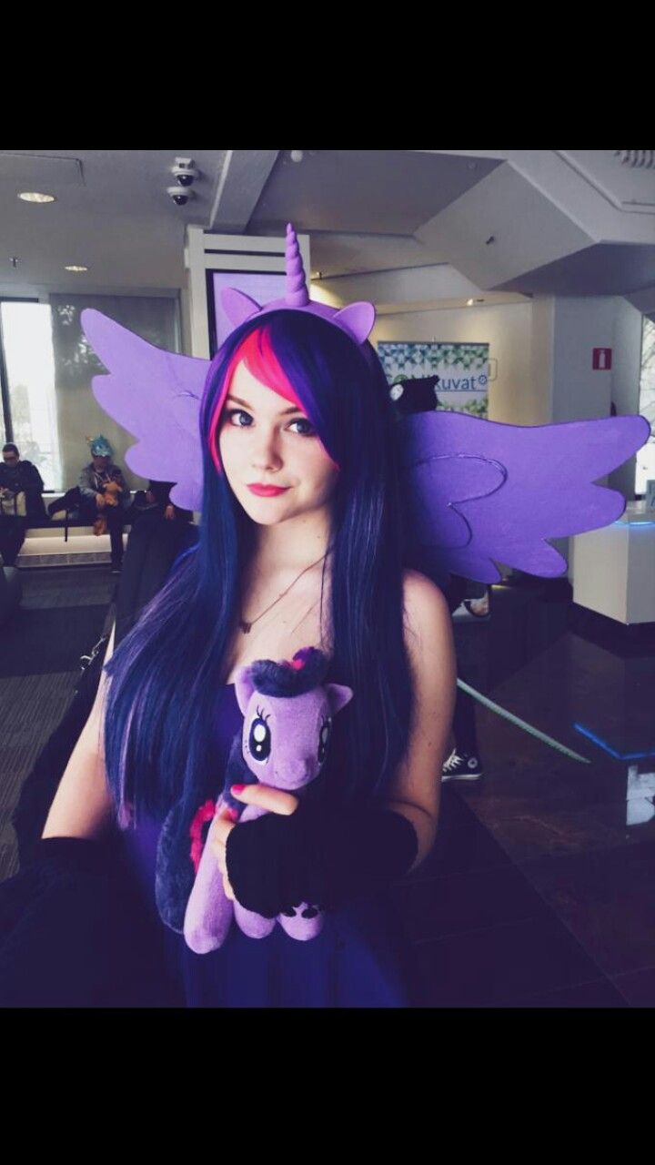 a woman with long blue hair holding a purple stuffed animal in an office building,