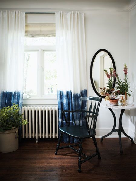 a chair sitting in front of a window next to a table with a mirror on it