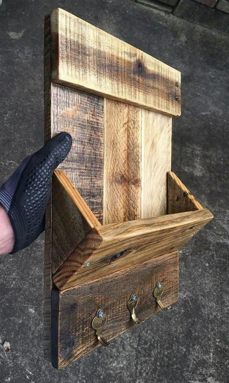 a person is holding a wooden box with two keys in it and the bottom part of the box has been made out of wood