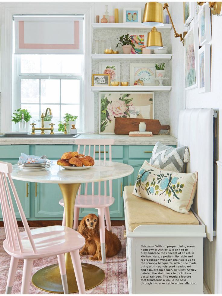 a dog sitting on the floor next to a table and chairs in a kitchen with blue cabinets