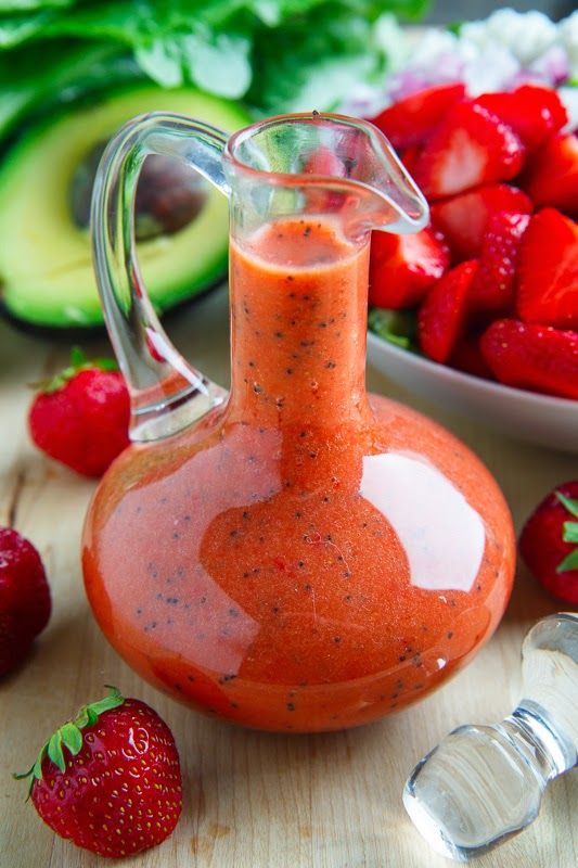 a glass pitcher filled with liquid next to strawberries and avocado