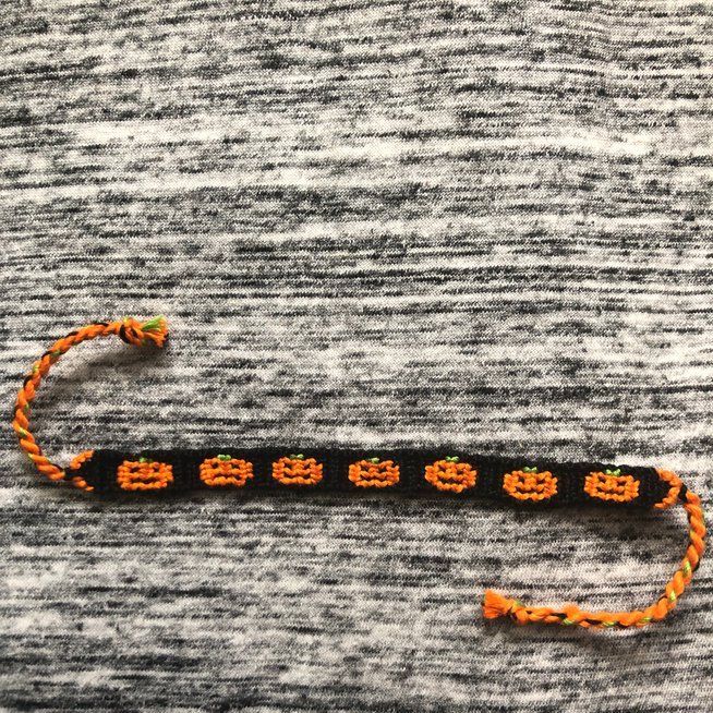 an orange and black beaded bracelet on top of a gray sweater with two skulls