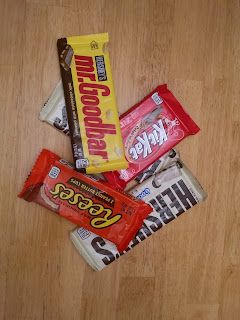 several different types of candy bars on a wooden table with one chocolate bar in the middle