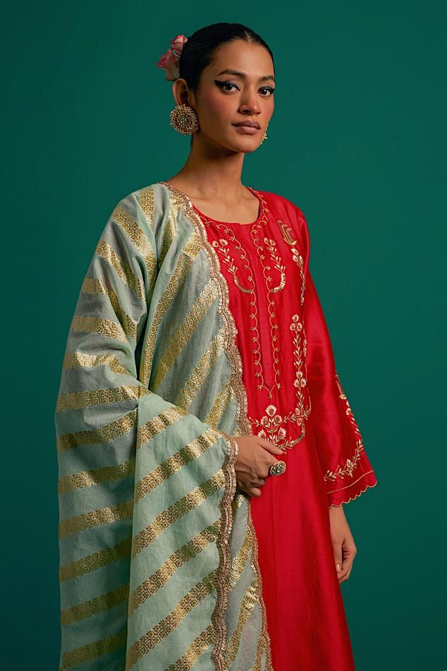 Red silk chanderi kurta with placed thread floral embroidery and scalloped edges. Comes with matching pant and contrast green dupatta.
Components: 3
Pattern: Embroidered
Type Of Work: Floral,Sequin
Neckline: Round
Sleeve Type: Full
Fabric: Kurta and Pant: Silk Chanderi, Dupatta: Chanderi
Color: Red
Other Details: 
Model Height: 5ft 6inches wearing size S
Closure: Kurta: Front hook
Occasion: Mehendi and Haldi - Aza Fashions Green Dupatta, Chanderi Dupatta, Red Kurta, Kurta With Pants, Scalloped Edges, Red Silk, Set For Women, Aza Fashion, Model Height