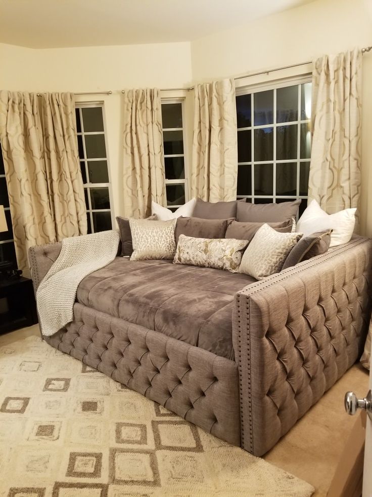 a large brown couch sitting in front of two windows