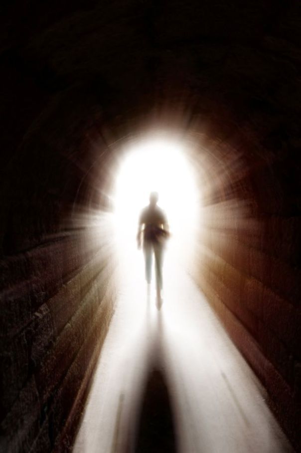 a man standing in the middle of a tunnel with light coming from behind his head