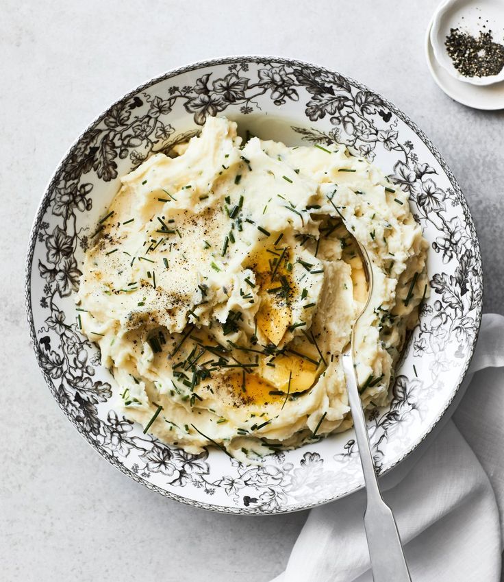 a bowl filled with mashed potatoes and gravy on top of a white table