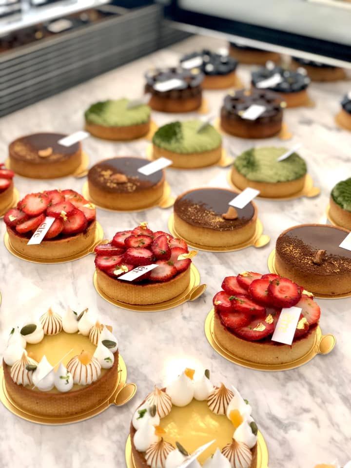 many different desserts are on display in a bakery case, including strawberries and other pastries