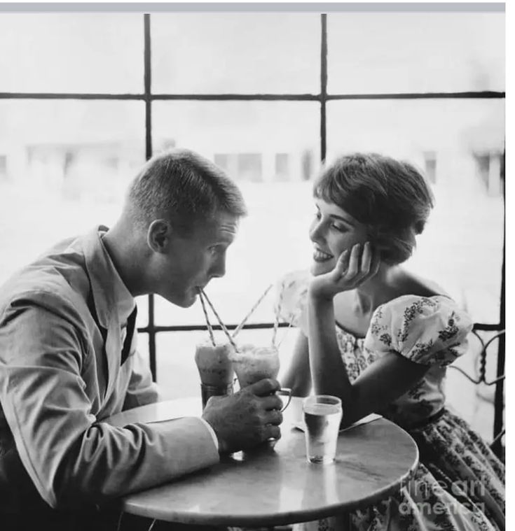 a man and woman sitting at a table with drinks