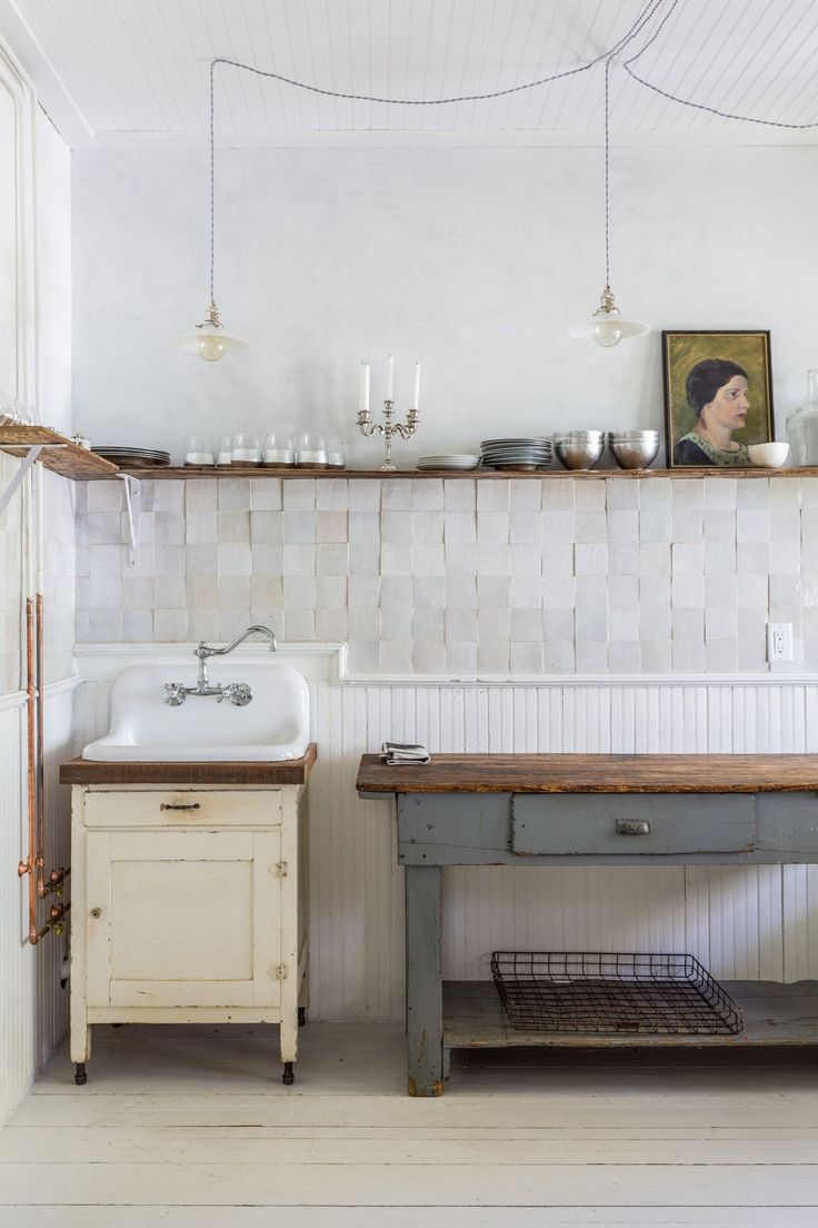 an old fashioned kitchen with white tiles and wooden counter tops, including a farmhouse sink