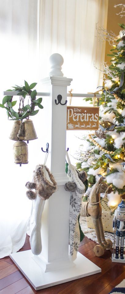 a christmas tree is decorated with stockings, bells and other holiday decorations in front of a window