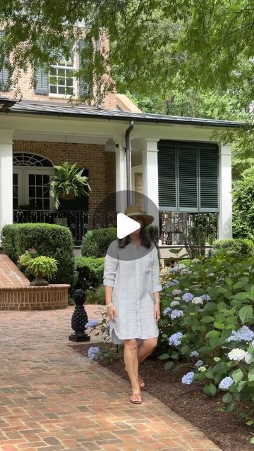 a woman walking down a brick walkway in front of a house