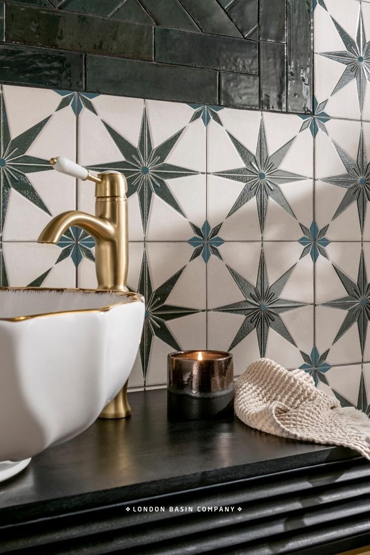 a bathroom sink with a gold faucet next to it on a black counter