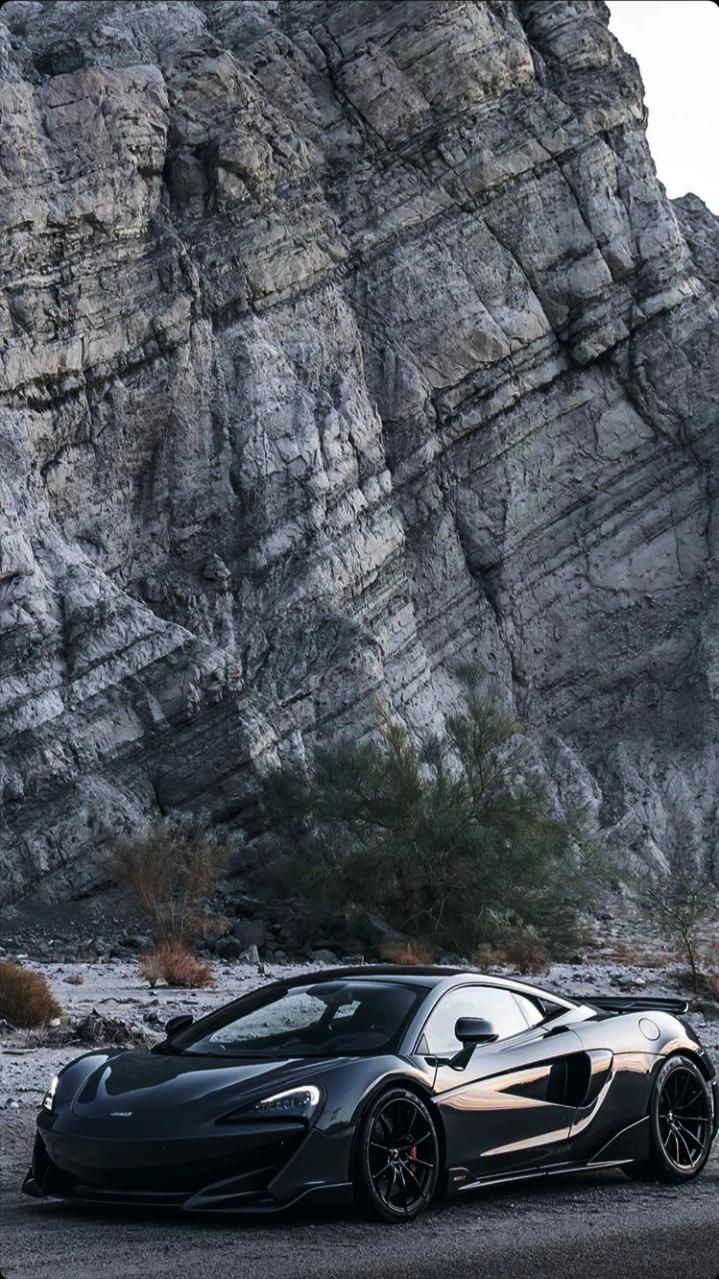 a black sports car parked in front of a mountain