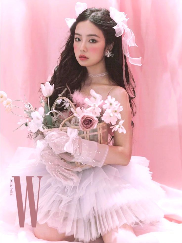 a woman in a white dress is holding flowers and posing for a photo with the letter w