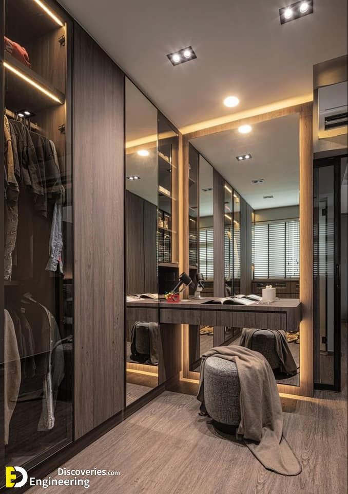 a walk in closet with mirrored doors and lights on the ceiling, along with a dressing area