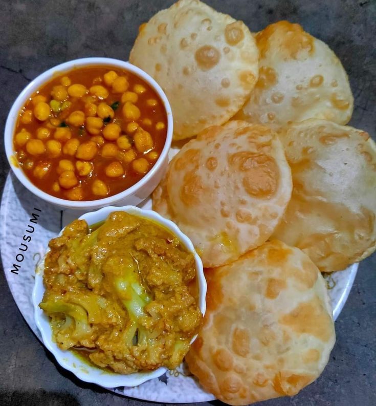 a plate topped with bread and bowls filled with different types of food next to each other