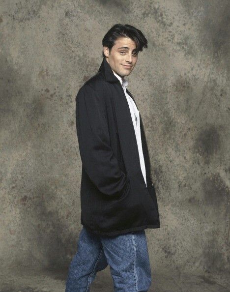 a young man is dressed in jeans and a black jacket, posing for the camera