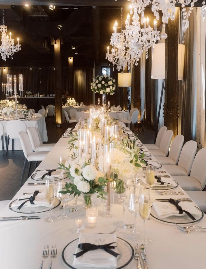 a long table is set with white flowers and place settings for an elegant dinner party