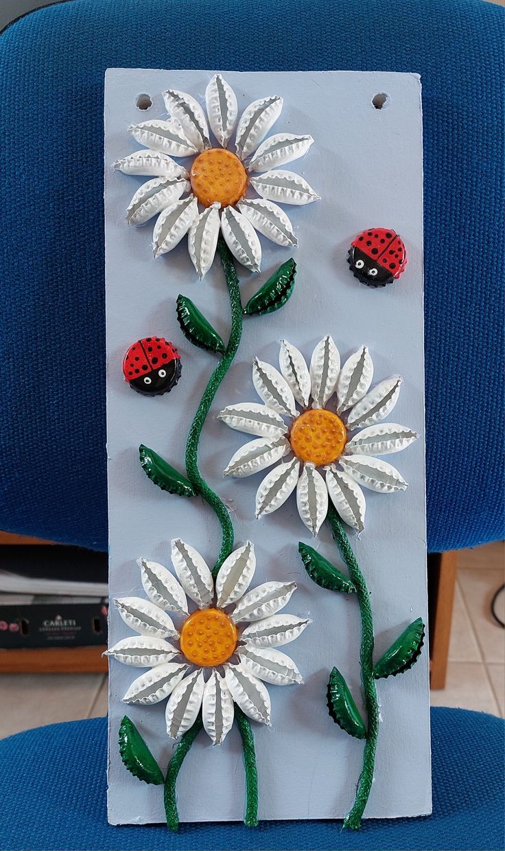 a card with flowers and ladybugs on it sitting on a blue chair in front of a computer keyboard