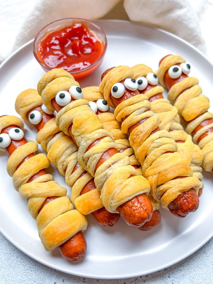 hot dogs wrapped in bread with googly eyes on them and ketchup for eyes