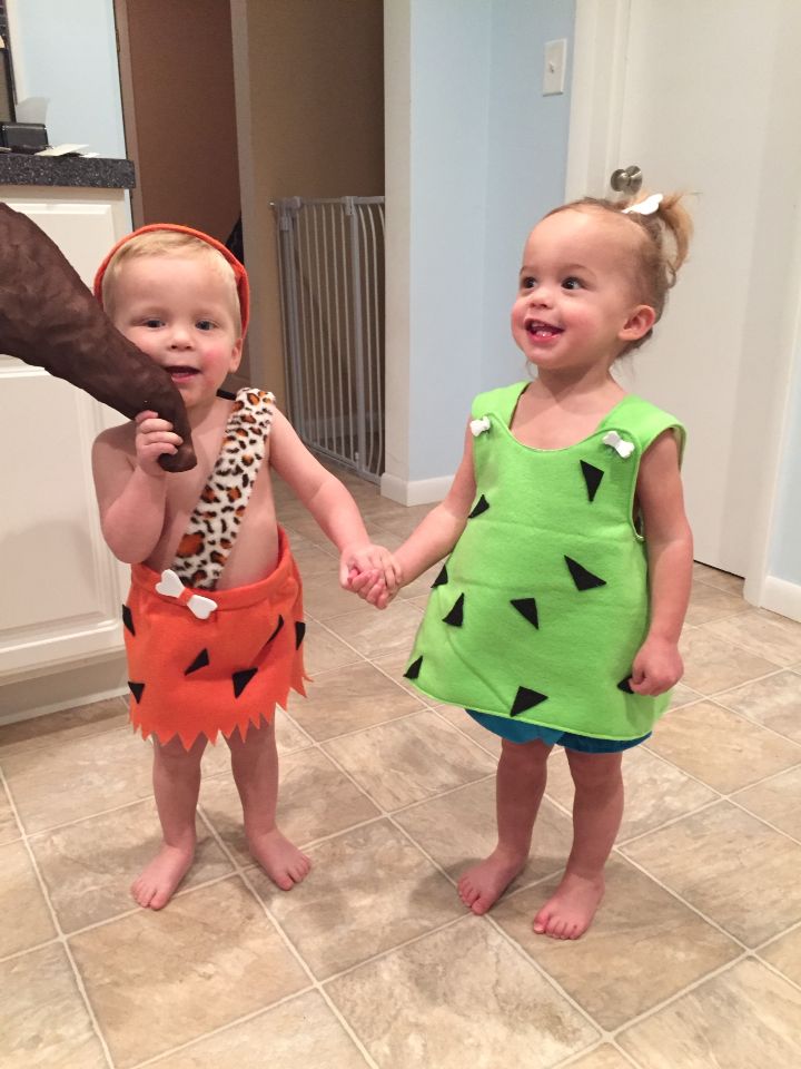 two young children in costumes holding hands