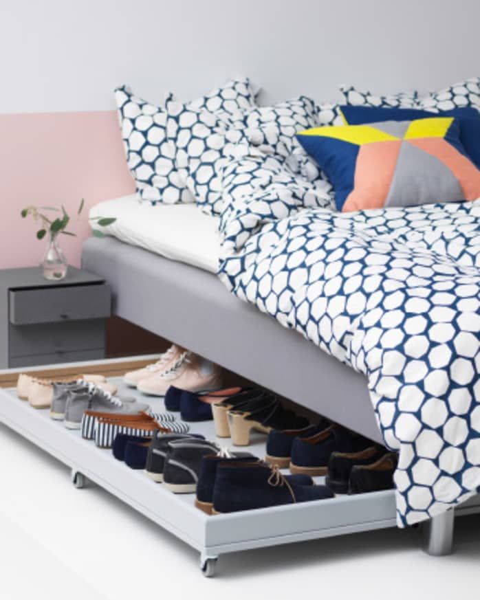 a bed sitting on top of a white floor next to a dresser with shoes in it