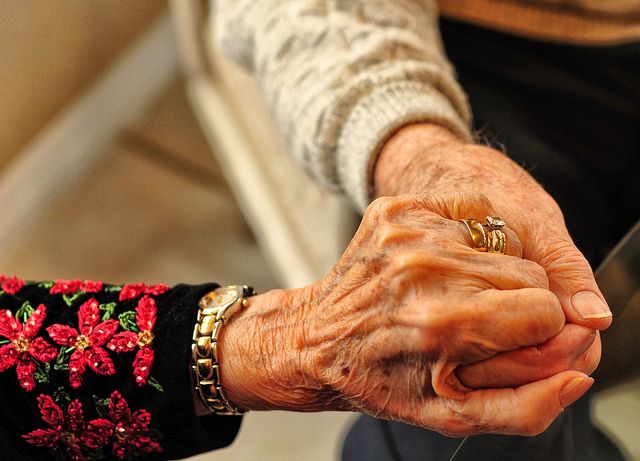 an elderly woman holding the hand of another person