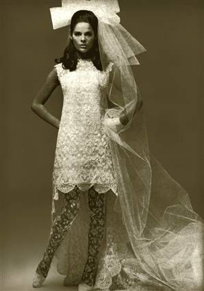 a woman in white dress and veil standing next to a mannequin wearing patterned pants