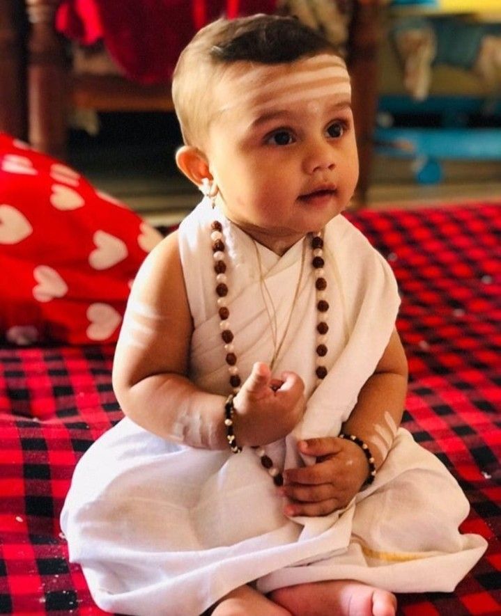 a small child sitting on top of a red and black checkered tablecloth covered floor