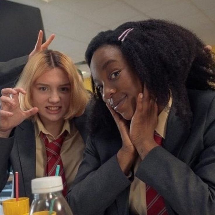 two women sitting at a table with their hands in the air and one holding her head