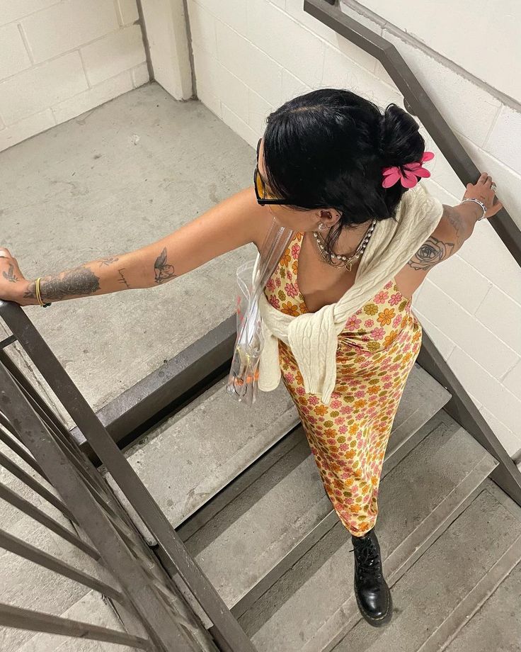 a woman climbing up the stairs with her hand in her pocket and tattoo on her arm