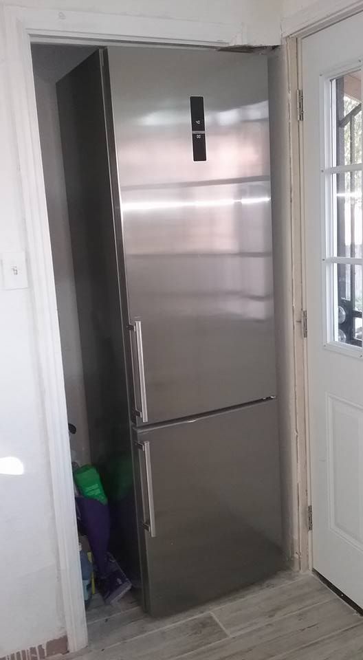 a stainless steel refrigerator in the corner of a room next to a white door and window