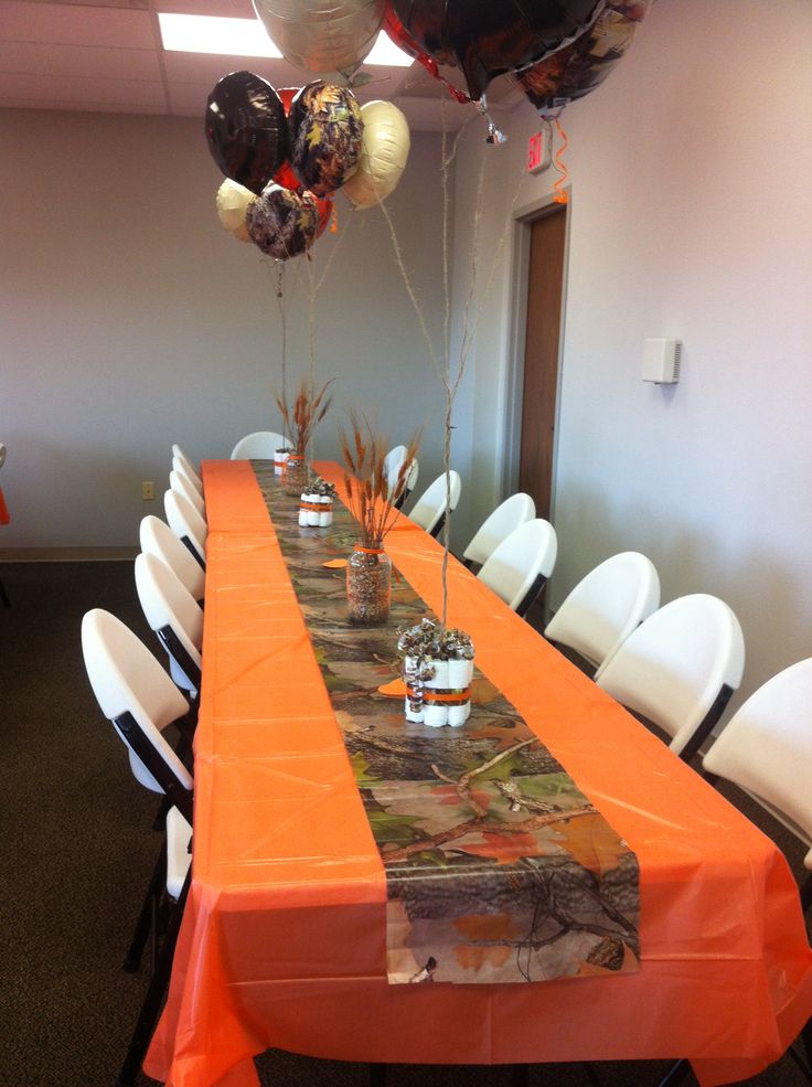 an orange table cloth is set up for a party with balloons in the shape of camo