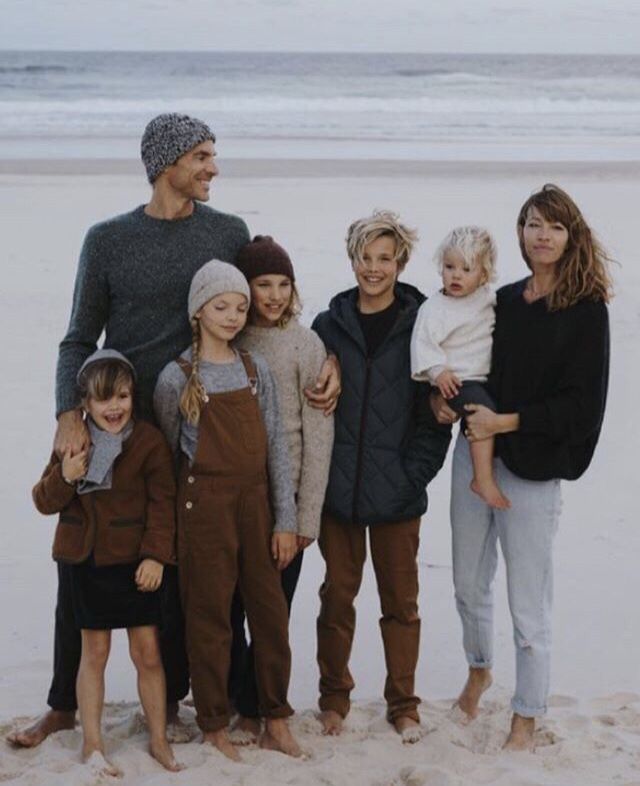 a group of people standing next to each other on top of a sandy beach near the ocean