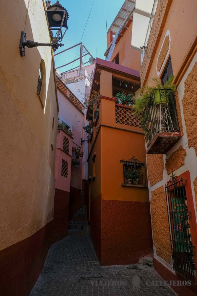 an alley way with colorful buildings on both sides and a lamppost in the middle