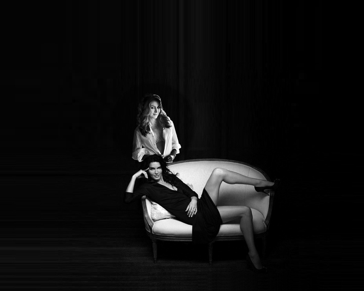 two people sitting on a couch in the dark with one person laying on the chair