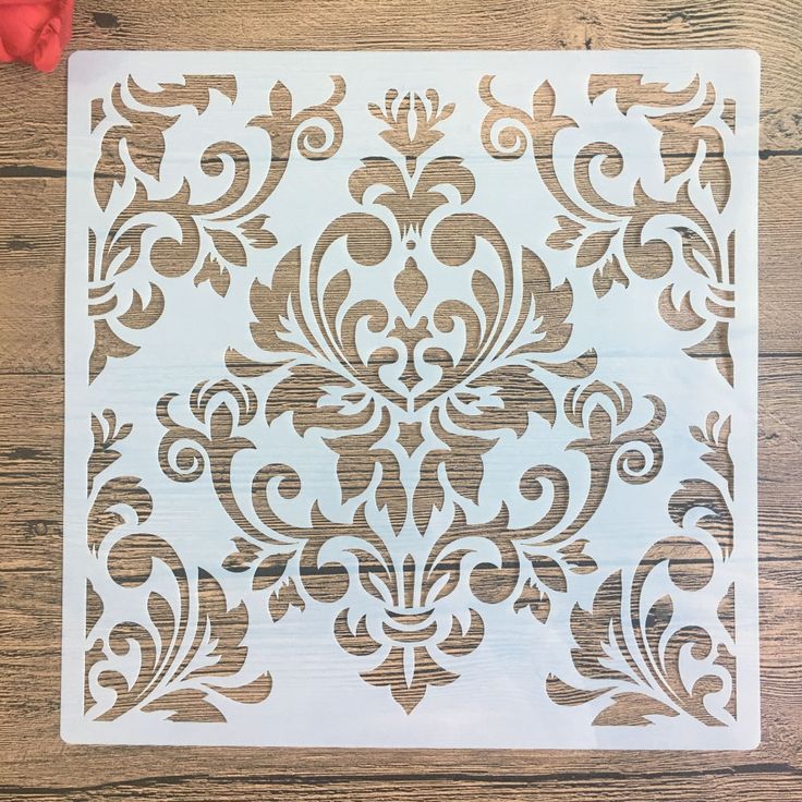 the stencil is being used to make a damask pattern on a piece of wood