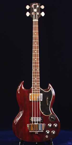 a red guitar sitting on top of a wooden stand