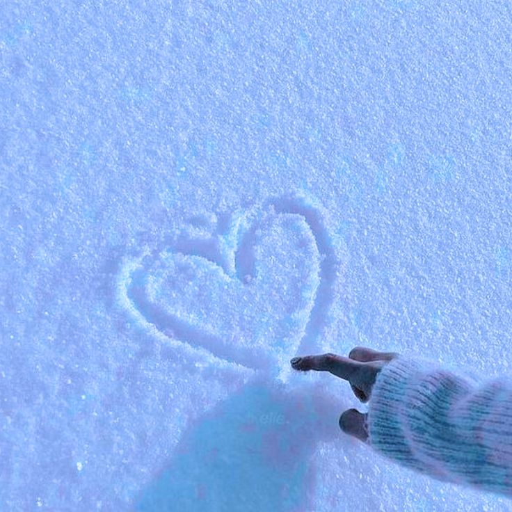 a person standing in the snow with a heart drawn on it