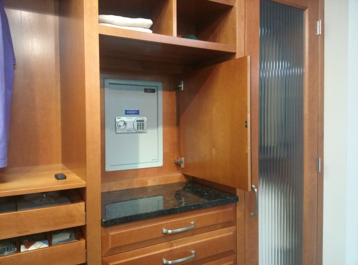 a bathroom with wooden cabinets and black marble counter tops, including an electronic device on the cabinet door