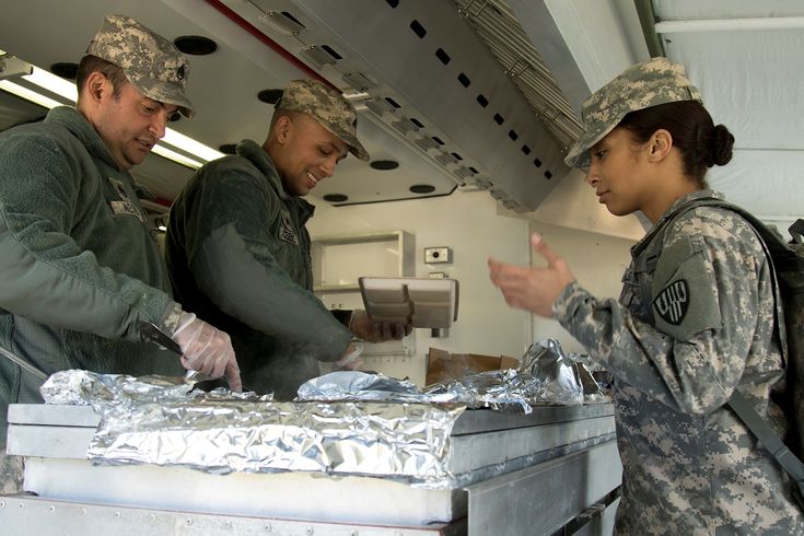 three soldiers are preparing food in the back of an aircraft with aluminum foil wrapped around them