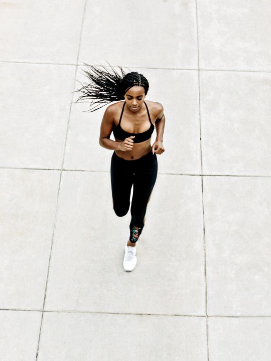 a woman running down a sidewalk with her hair blowing in the wind