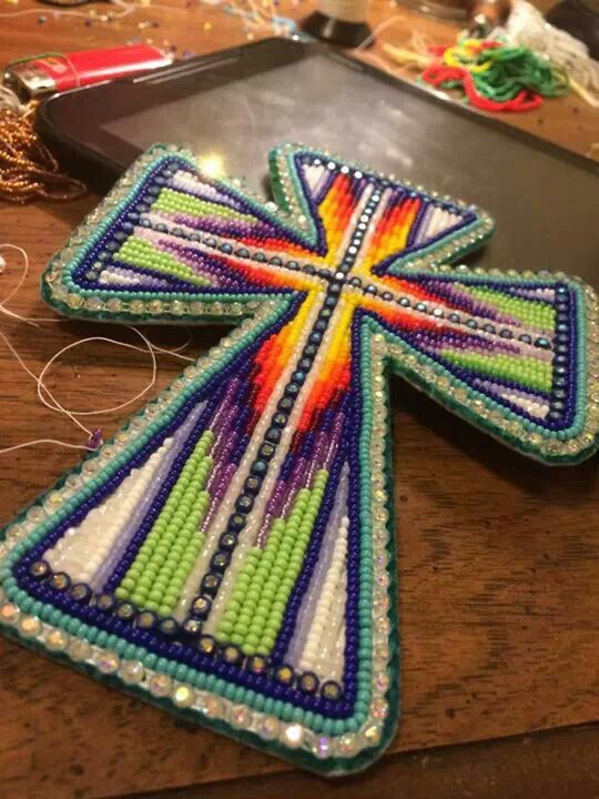 a cross made out of beads sitting on top of a wooden table next to a pan