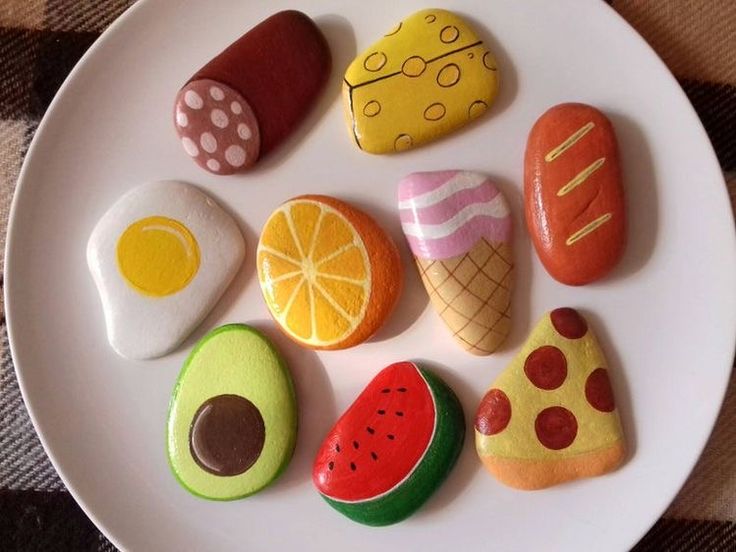 a white plate topped with rocks covered in different types of fruit and veggies