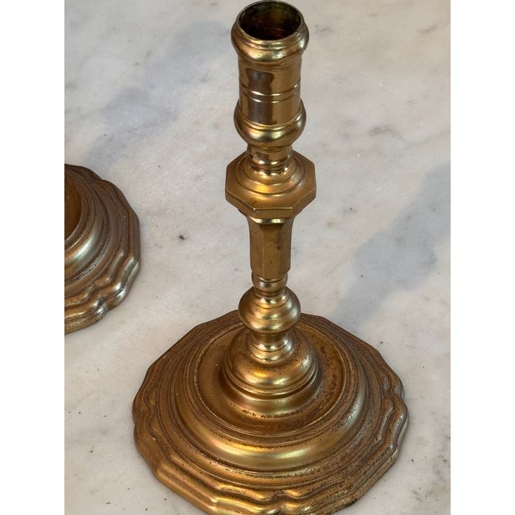 two brass candlesticks on a marble table